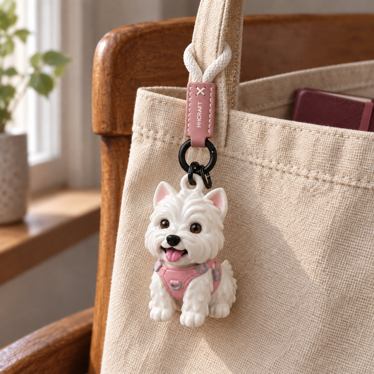 Illustrative Westie keychain attached by its braided loop to a canvas tote handle